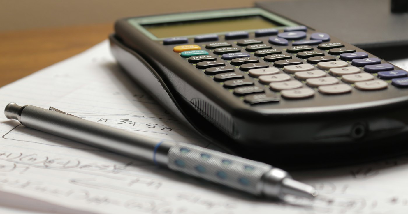 Calculator and pen on top of household bills