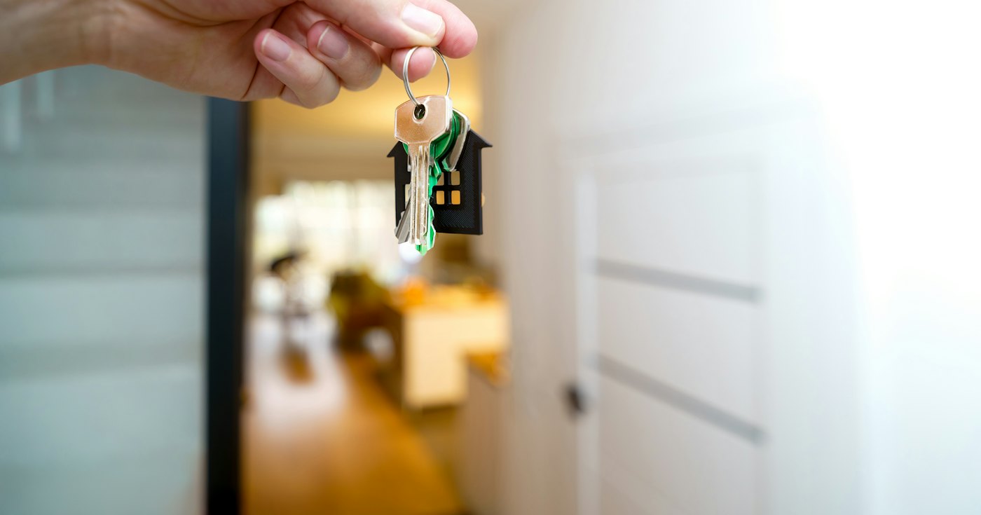 A hand holding house keys in front of a front door