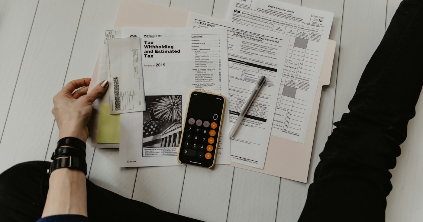 A person reviewing papers next to a calculator
