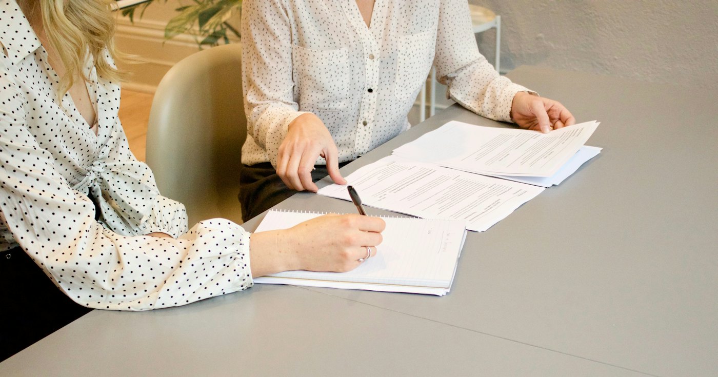 Two people reviewing and signing legal paperwork at a table