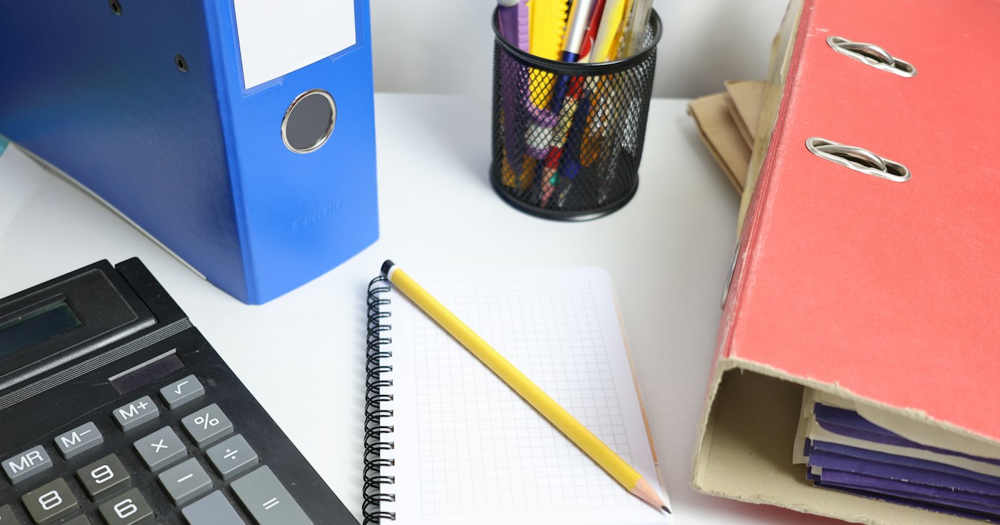 Desk with binders, a calculator and a notebook