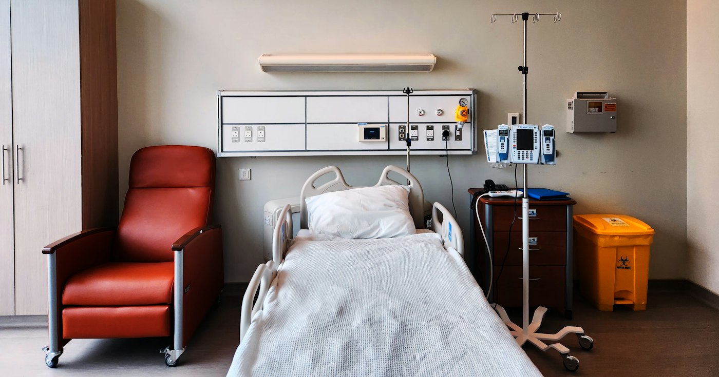 An empty hospital room with a bed and a chair