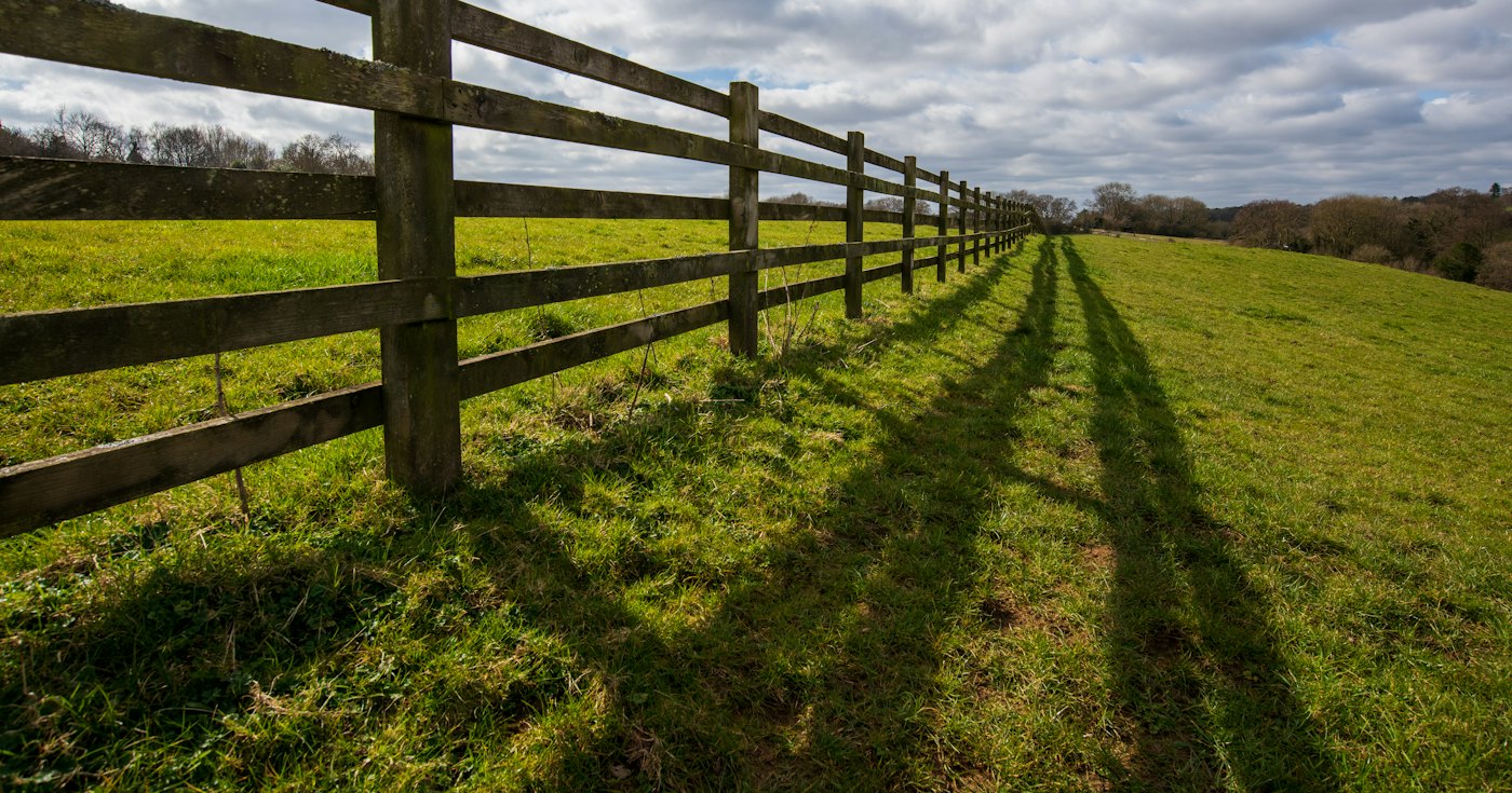 A long wooden fence running across a grassy field