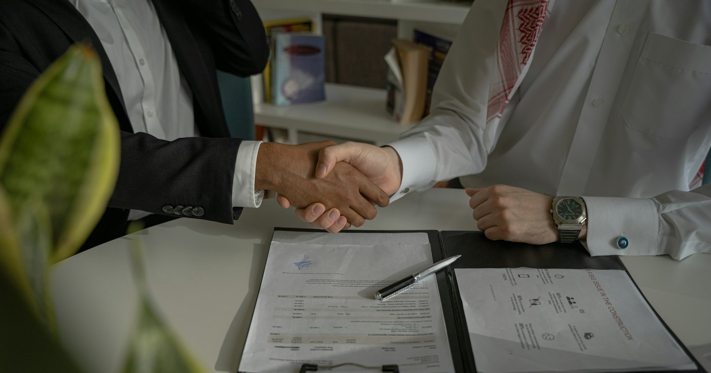 Two people shaking hands over a signed document