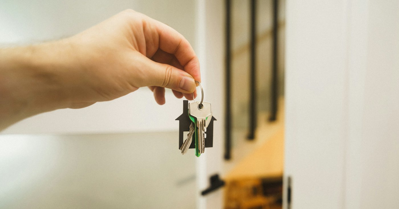 A hand holding a key to a front door